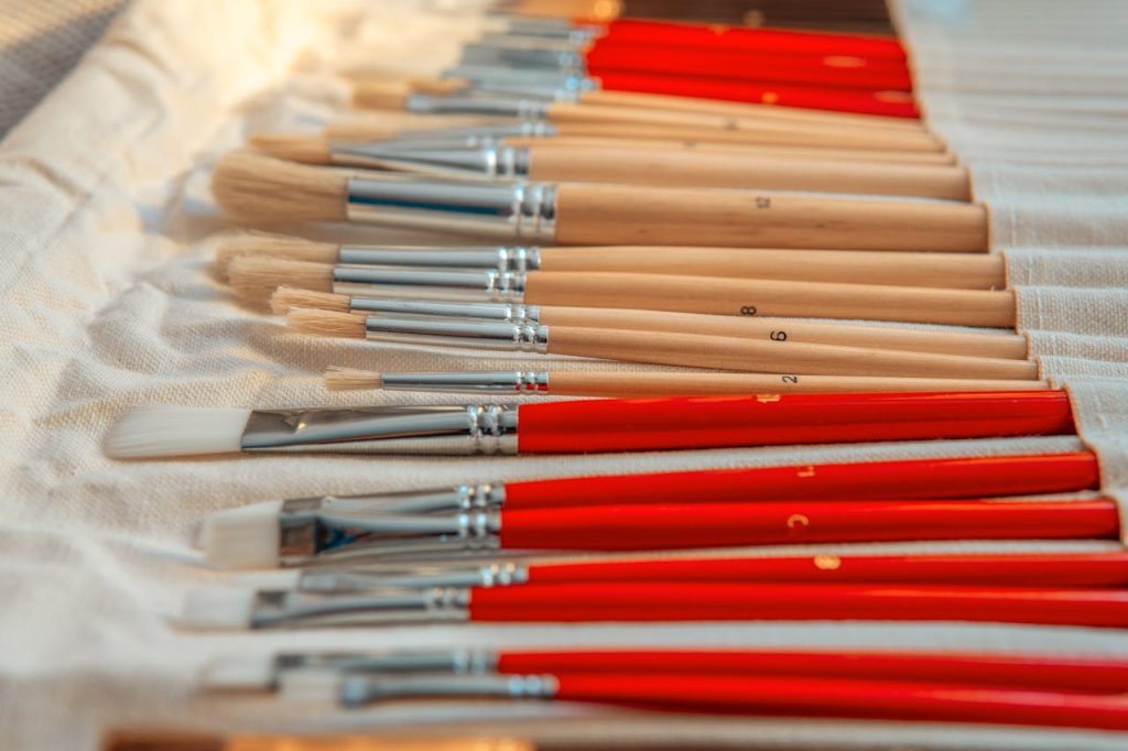 Close-up of assorted art paintbrushes neatly arranged on canvas fabric.